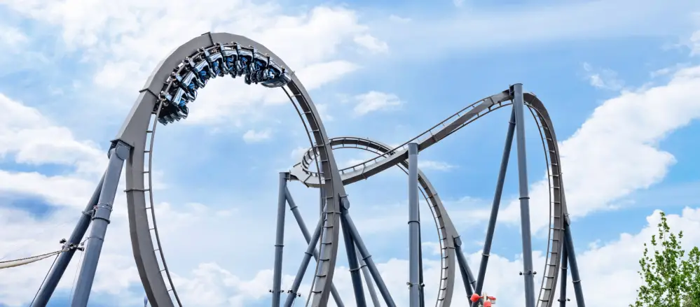 The Decepticoaster roller coaster at Universal Studios Beijing featuring a train full of riders going through a high-speed vertical loop against a bright blue sky.