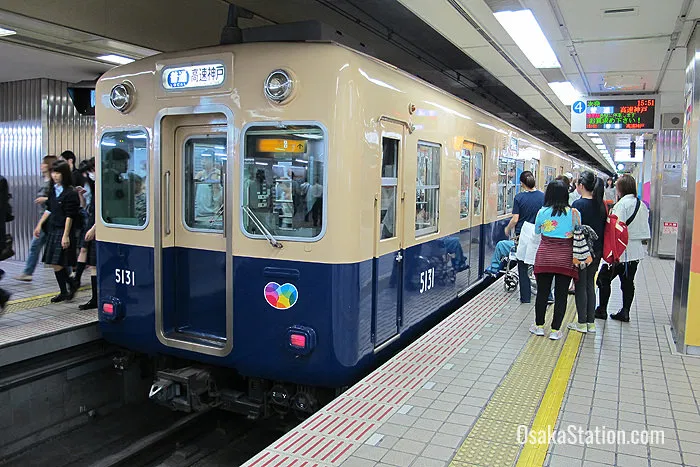 A cream and blue Hanshin Electric Railway local train car numbered 5131 stopped at an underground station platform while passengers wait to board.