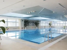 Spacious indoor swimming pool at Holiday Inn Beijing Focus Square with blue water, large windows, and natural light.