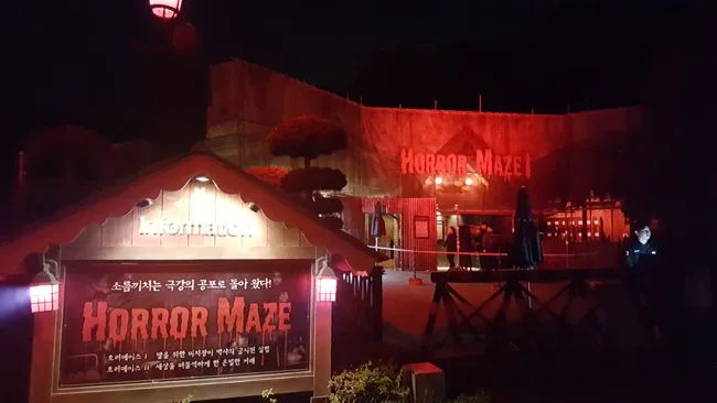 Entrance to the Horror Maze haunted attraction at Everland Theme Park illuminated in eerie red light at night.
