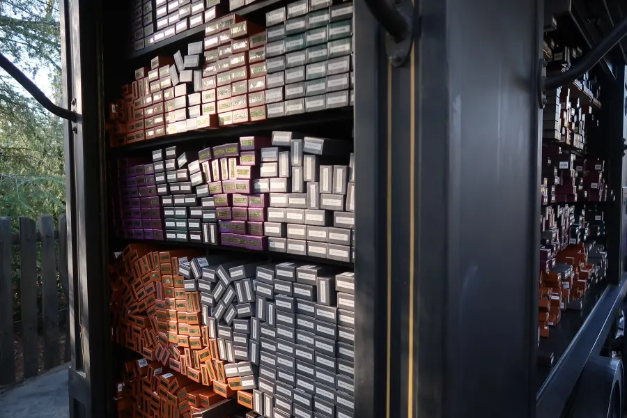 Close-up of a tall shelf inside a Harry Potter wand cart at Universal Studios Hollywood, displaying hundreds of stacked colorful wand boxes with labels