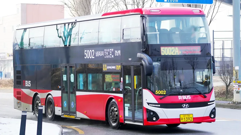 A red and white double-decker public express bus number 5002 driving on a road in South Korea.