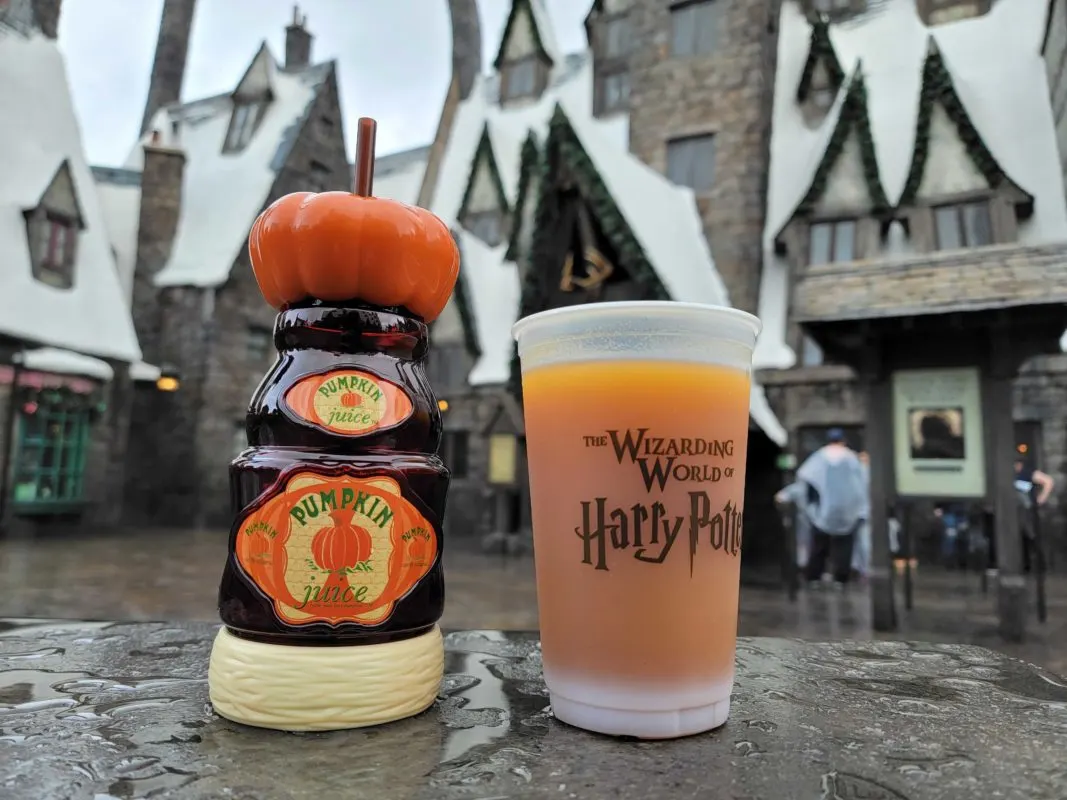 A plastic cup of orange Pumpkin Juice and a pumpkin-topped souvenir sipper bottle at The Wizarding World of Harry Potter in Universal Studios Hollywood