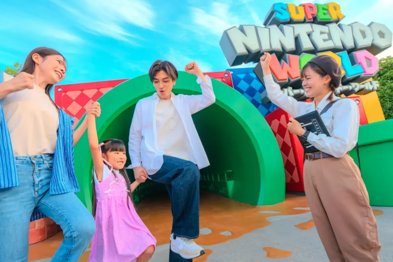 Family walking with a VIP guide into Super Nintendo World at Universal Studios Japan through the green warp pipe entrance.
