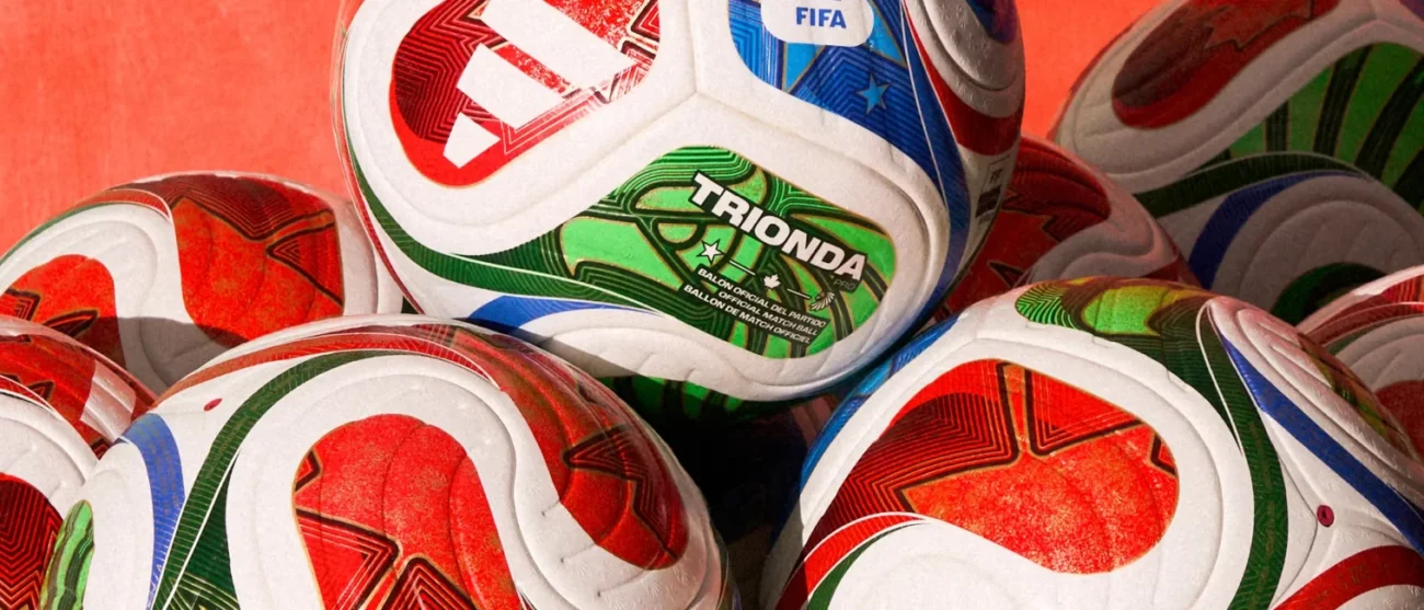 Close-up of a pile of official Trionda Pro FIFA match balls featuring vibrant red, green, and blue geometric patterns.