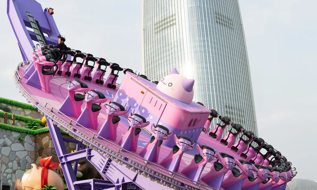 A thrilling purple spinning ride at Lotte World with riders tilted on a circular track, set against the backdrop of the tall Lotte World Tower in Seoul.