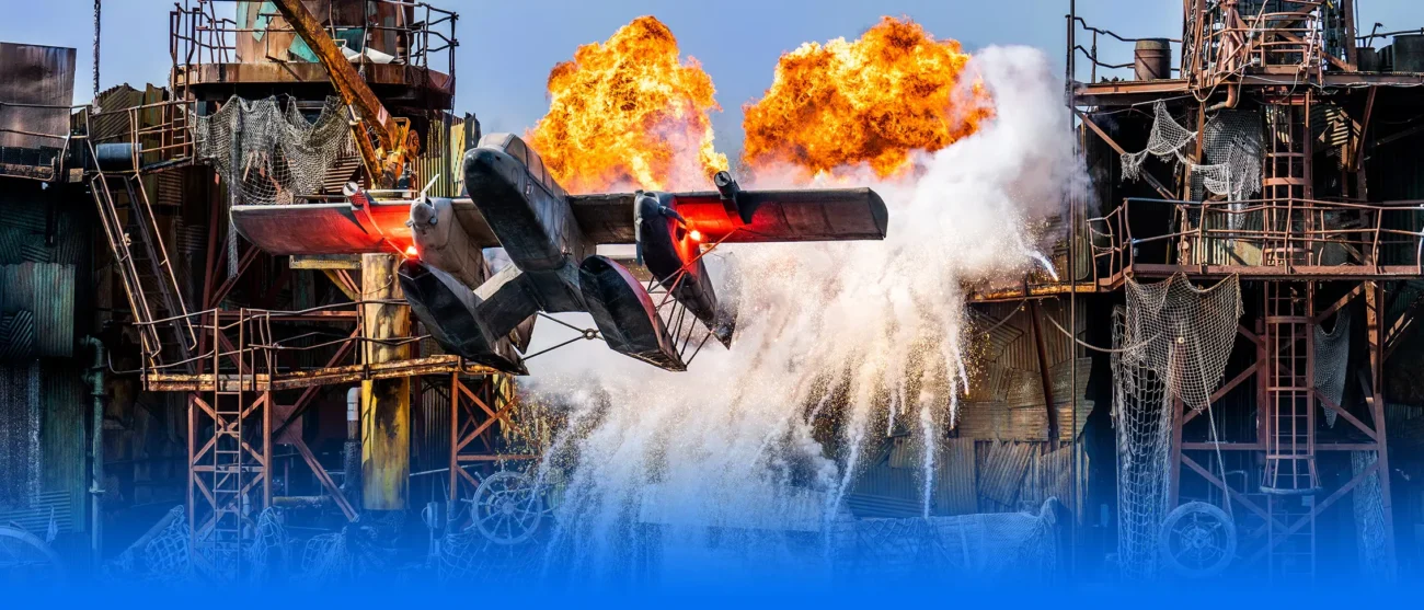 A dramatic sea plane crash stunt with large orange fire explosions and splashing water during the WaterWorld live show at Universal Studios Hollywood